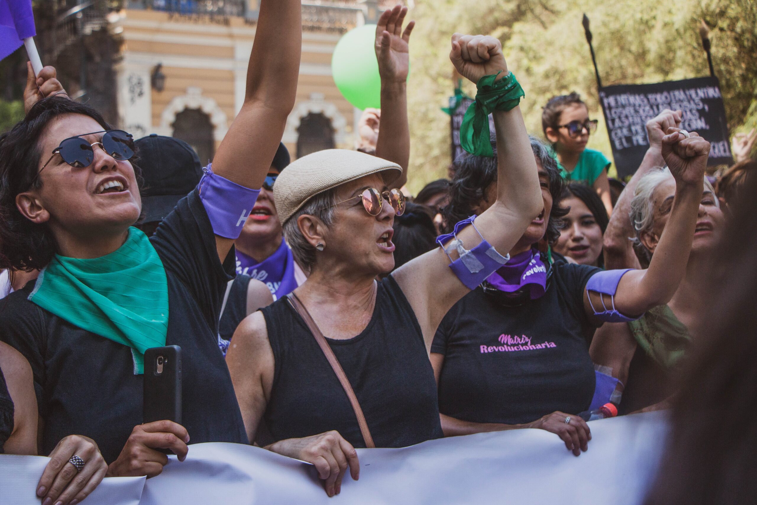 mujeres marchando por la igualdad con pañuelos verdes y morados